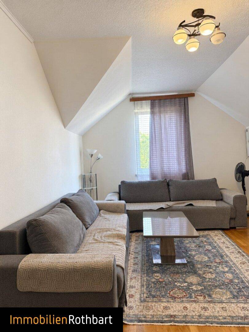 Gemütliches Wohnzimmer mit zwei Sofas, Couchtisch und Dachschräge, bietet viel Platz zum Entspannen.