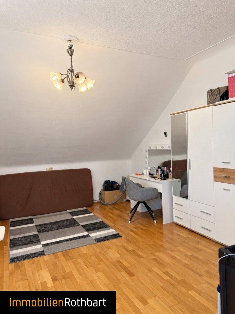 Schlafzimmer mit Dachschräge, Holzboden und Schminktisch, bietet eine persönliche Rückzugsmöglichkeit.