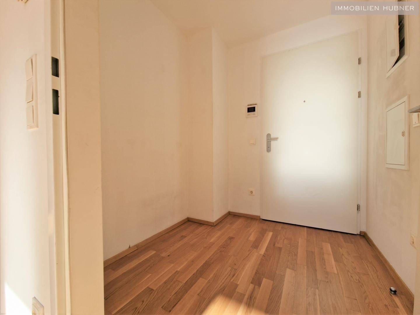 Eingangsbereich mit Parkettboden und weißer Wohnungstür, hell und einladend.