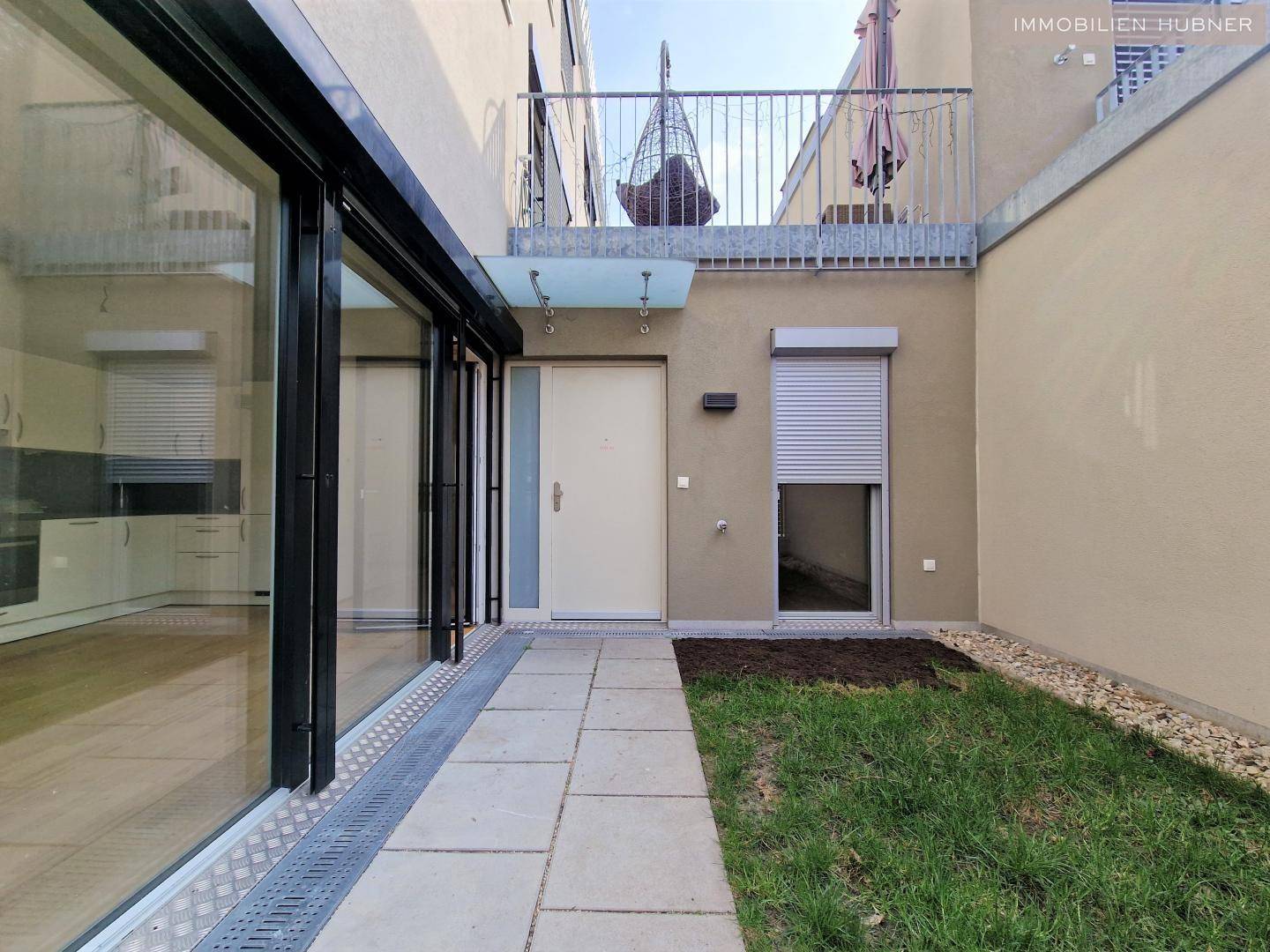 Eingangsbereich eines modernen Hauses mit kleiner Grünfläche und Zugang zu den Innenräumen.