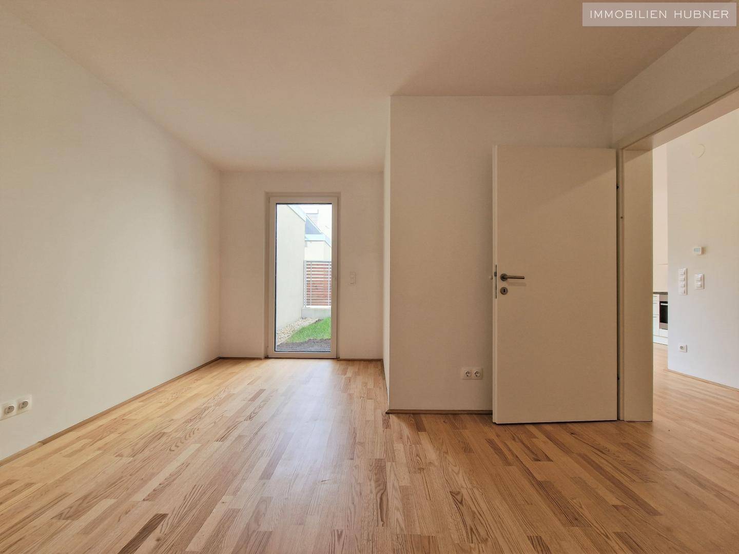 Geräumiges Zimmer mit Parkettboden und weiß gestrichenen Wänden, ideal als Schlafzimmer.