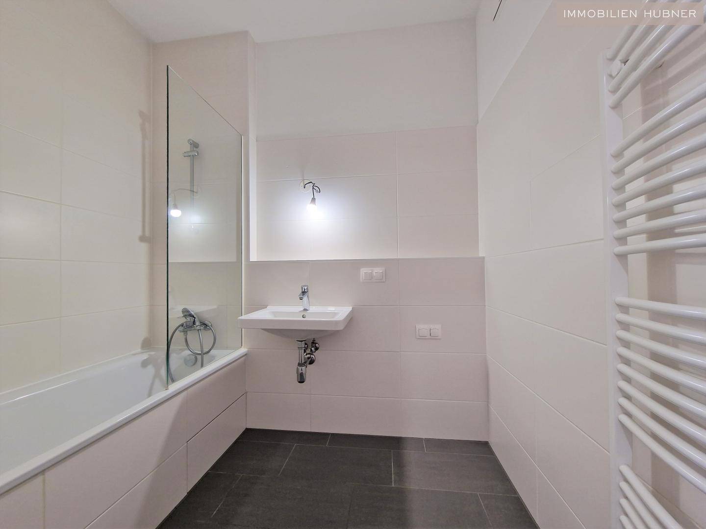 Modernes Badezimmer mit Badewanne, Waschtisch und beheiztem Handtuchhalter.