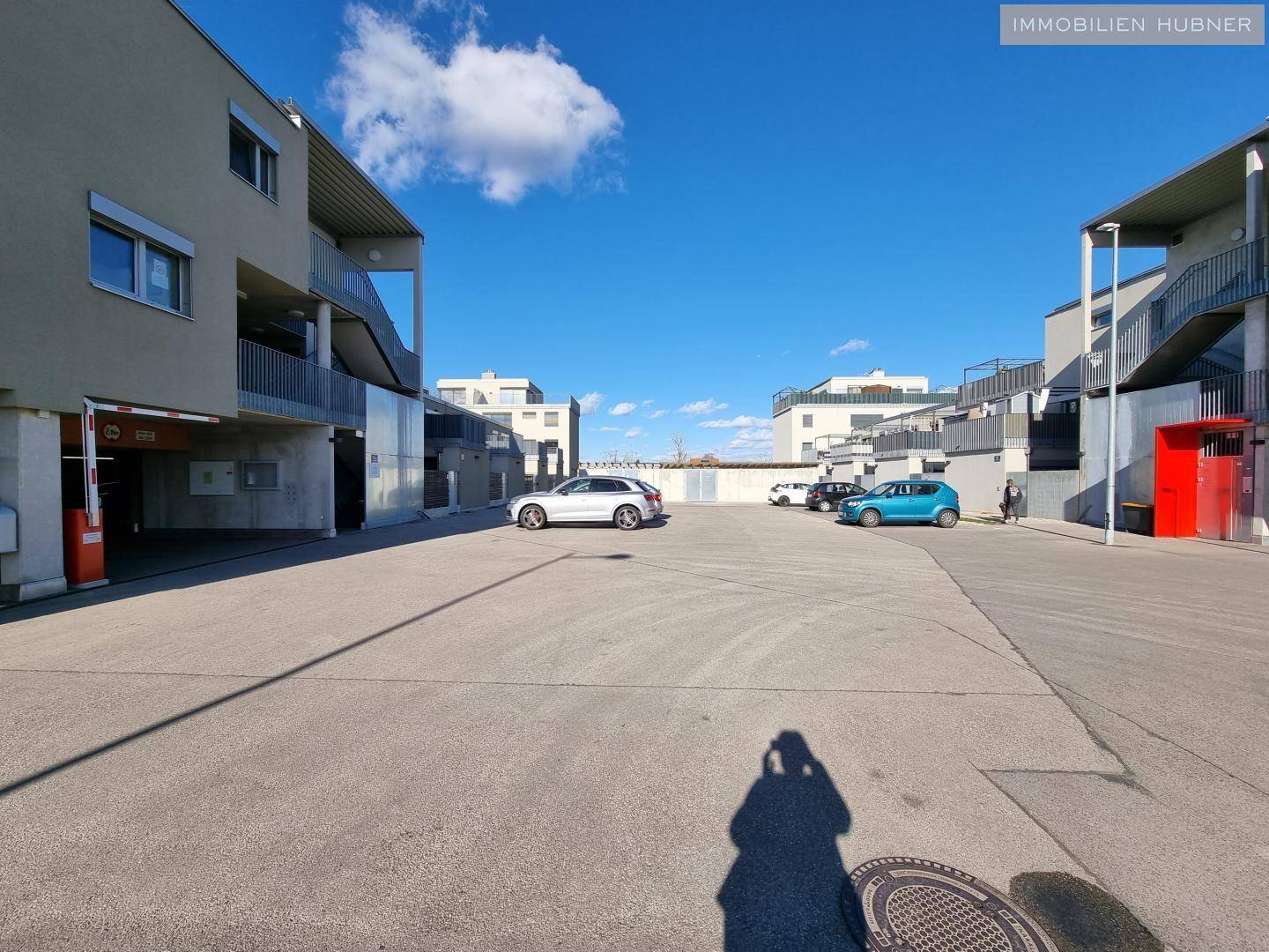 Außenbereich der Wohnanlage mit Parkplätzen und Zufahrt zur Tiefgarage.