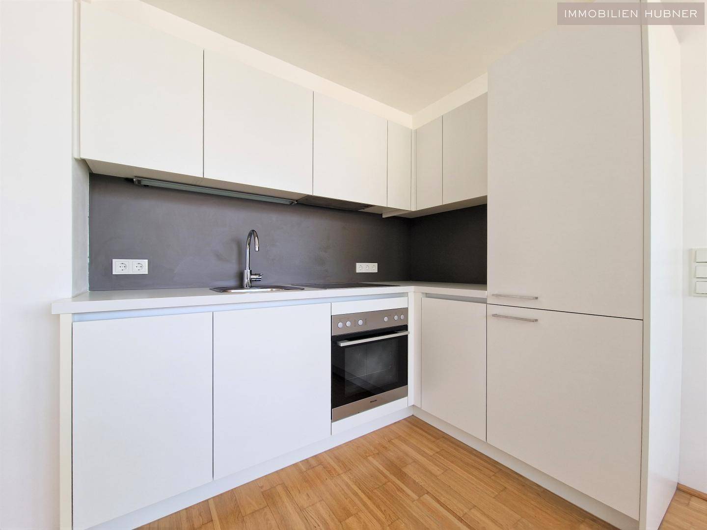 Moderne weiße Einbauküche mit integriertem Backofen und Spülbecken, funktional und stilvoll.
