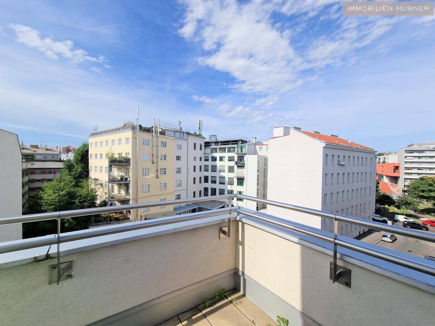 Weitblick von der Terrasse über die Dächer der Stadt unter einem strahlend blauen Himmel.