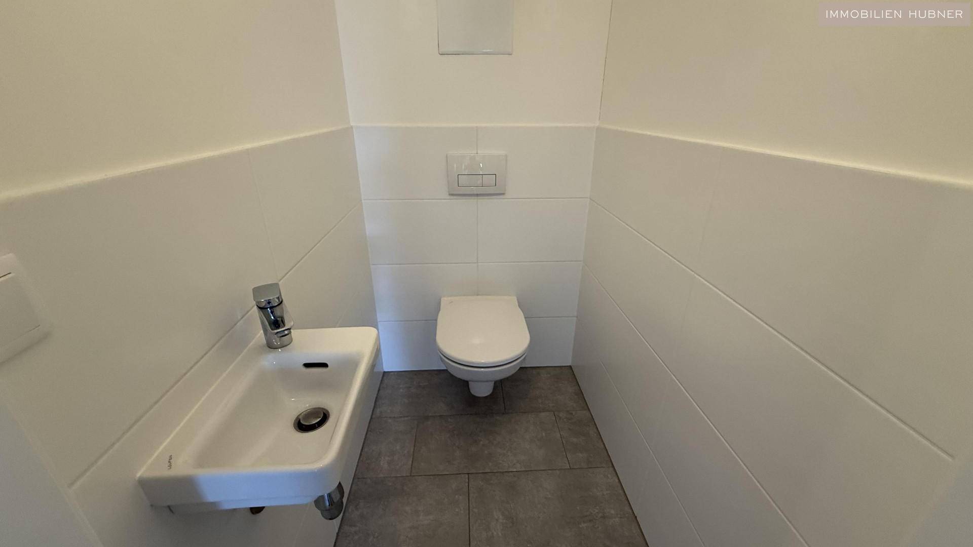 Separates Gäste-WC mit Wand-WC und kleinem Handwaschbecken.