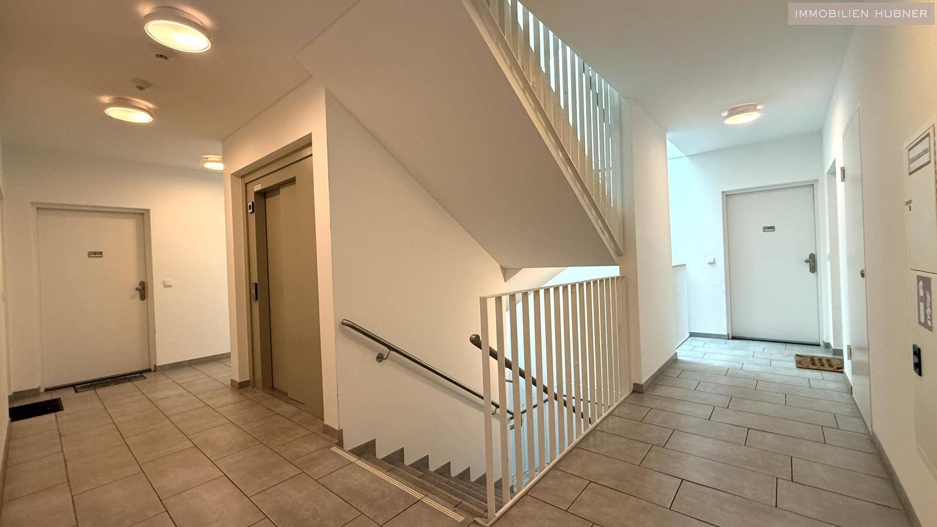 Heller Treppenaufgang und Flur im Mehrfamilienhaus mit Aufzug.
