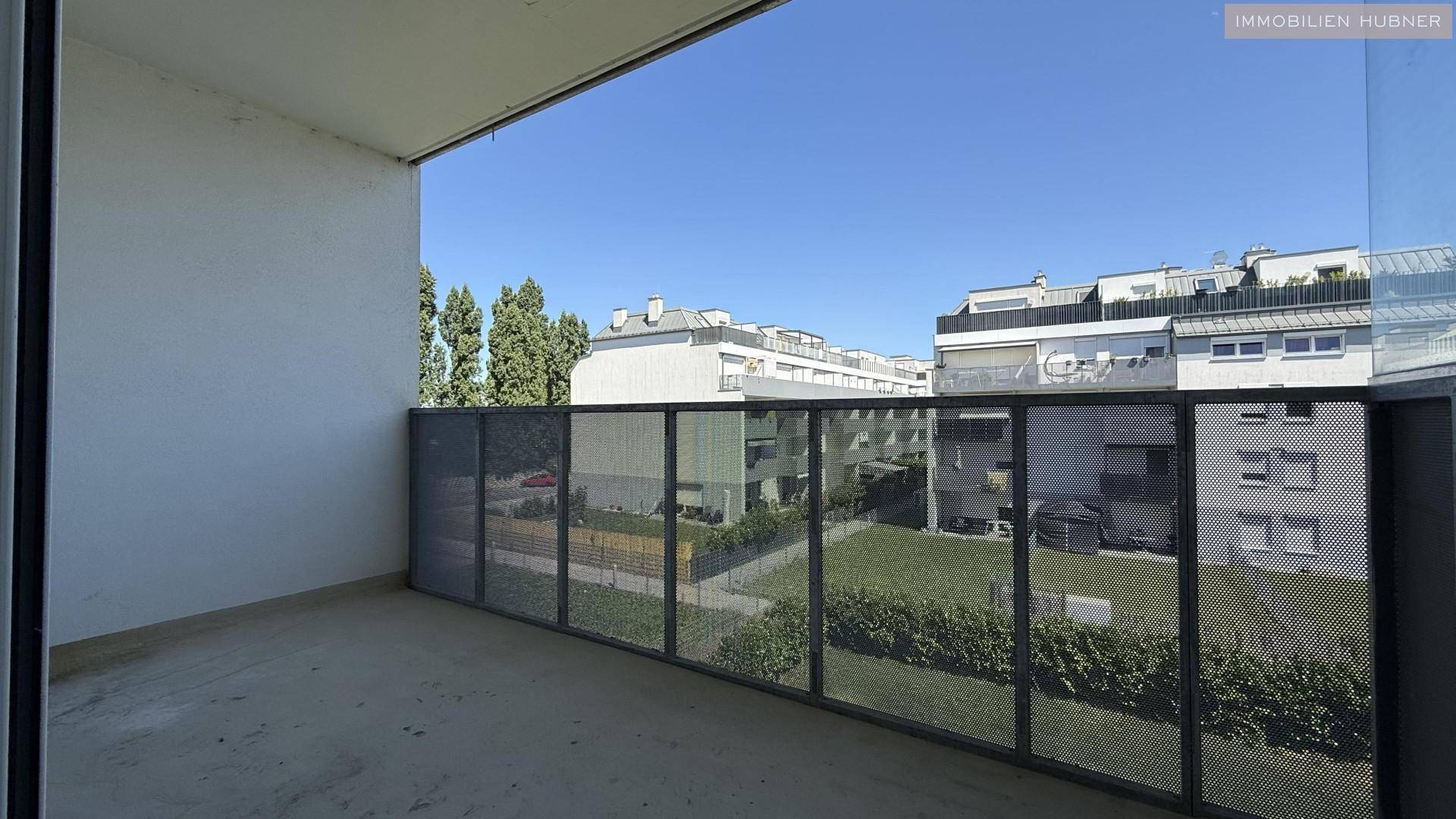 Geräumiger Balkon mit Blick auf den begrünten Innenhof und umliegende Gebäude.