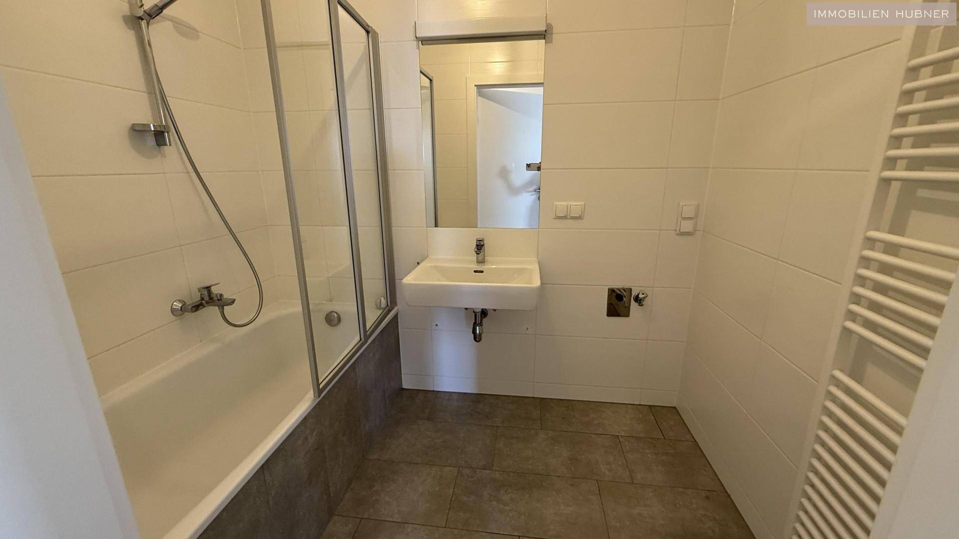 Modernes Badezimmer mit Badewanne, Duschabtrennung und Waschbecken.