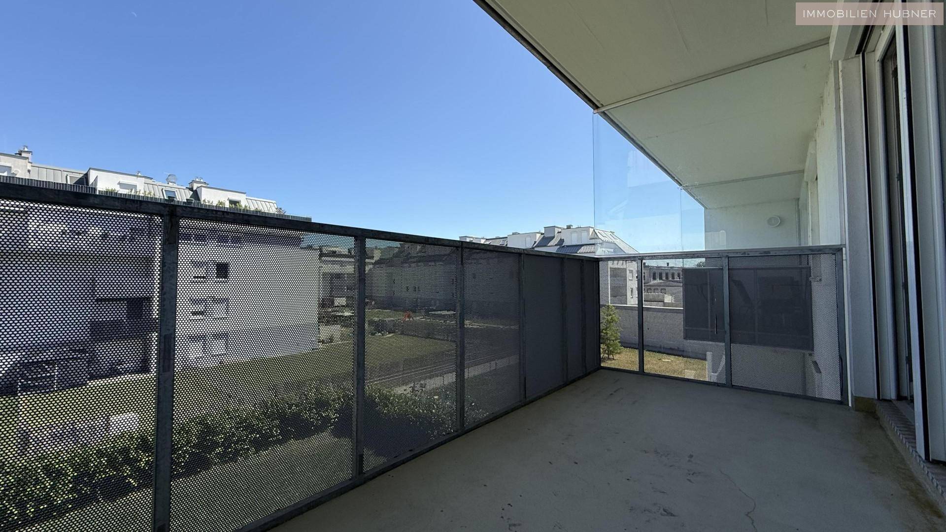 Moderner Balkon mit Glasbrüstung und Blick auf die Nachbarschaft.