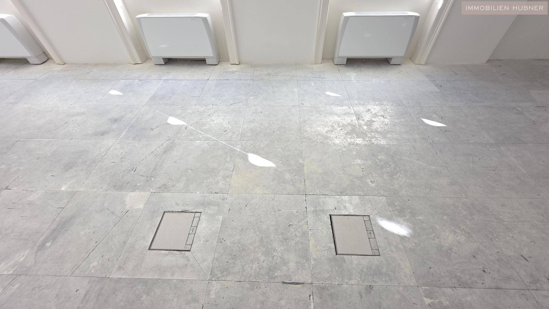 Detailaufnahme des Betonbodens mit Bodentanks und Lichteinfall.