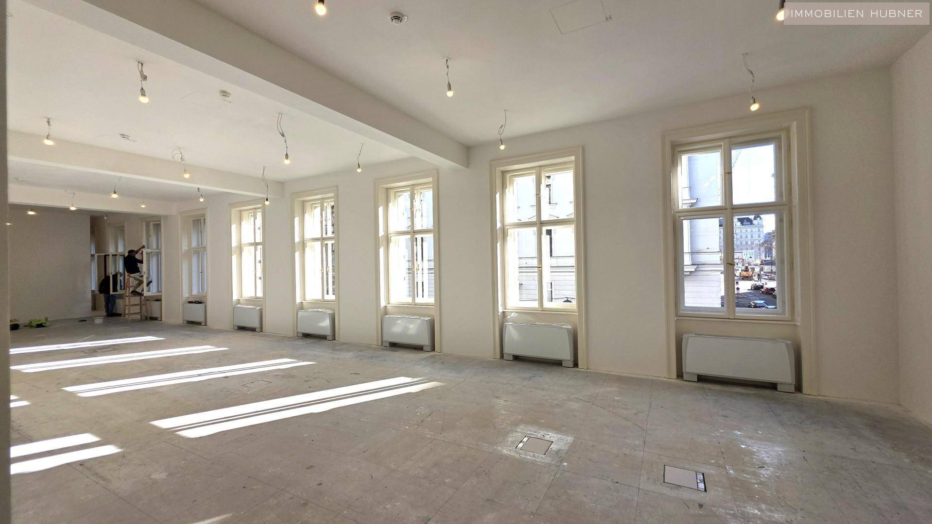 Heller, offener Bürobereich mit mehreren Fenstern, die den Raum mit Sonnenlicht durchfluten und eine angenehme Arbeitsumgebung bieten.
