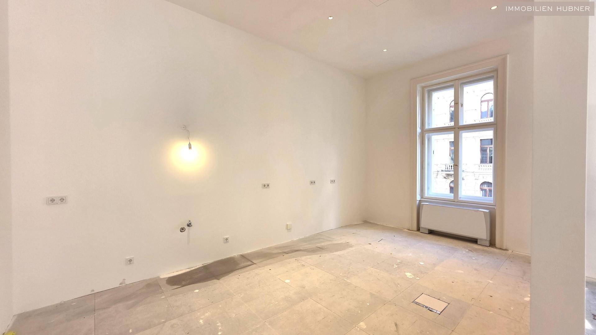 Kleinerer Raum mit einem Fenster und vorbereiteten Anschlüssen an der Wand, ideal für eine Teeküche oder ein Einzelbüro.