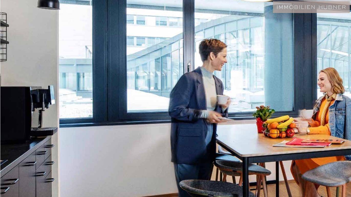 Helle Teeküche mit modernen Möbeln, Kaffeemaschinen und Blick auf den Innenhof.