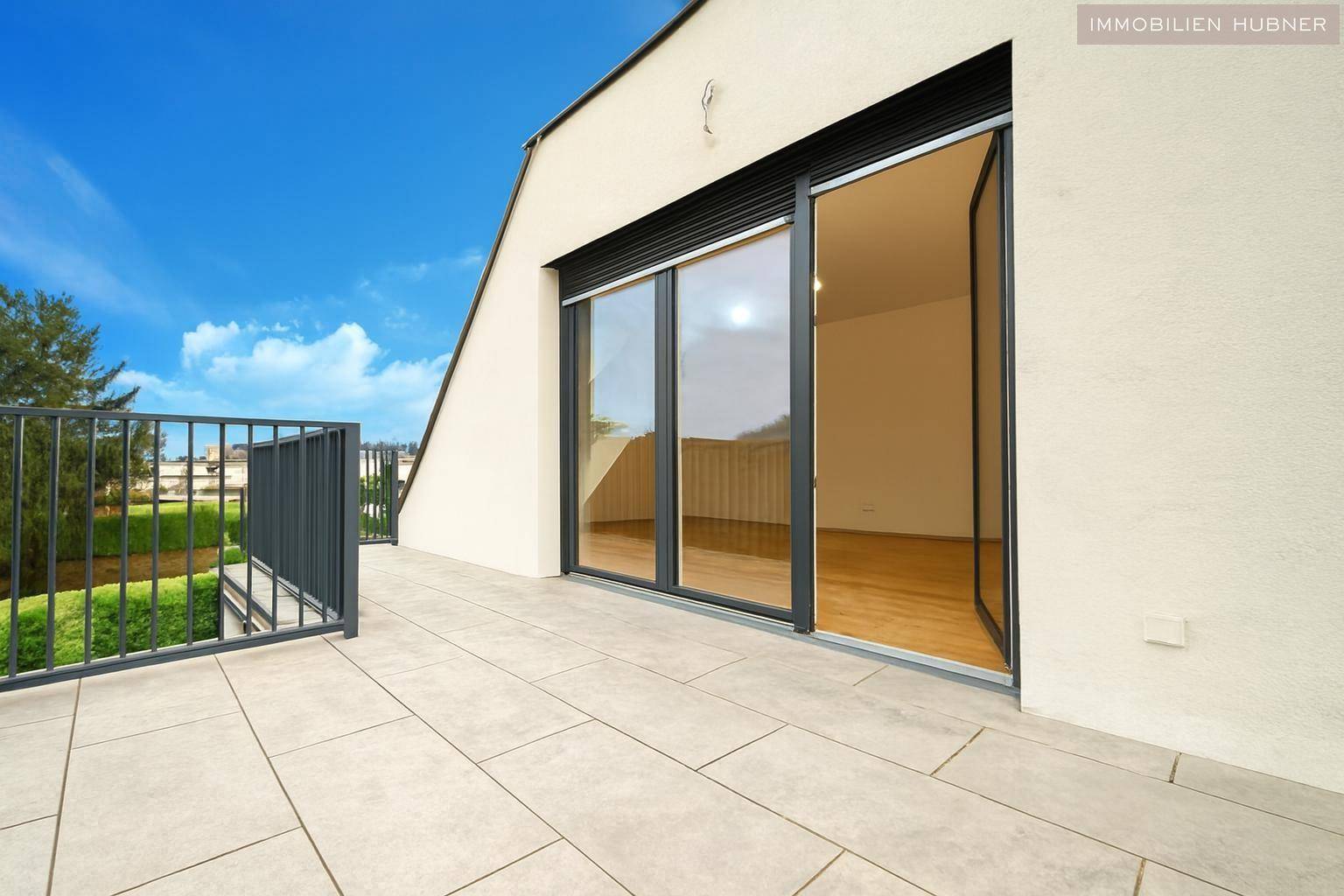 Große geflieste Terrasse mit Schiebetüren zum Innenbereich und Blick auf die Umgebung.