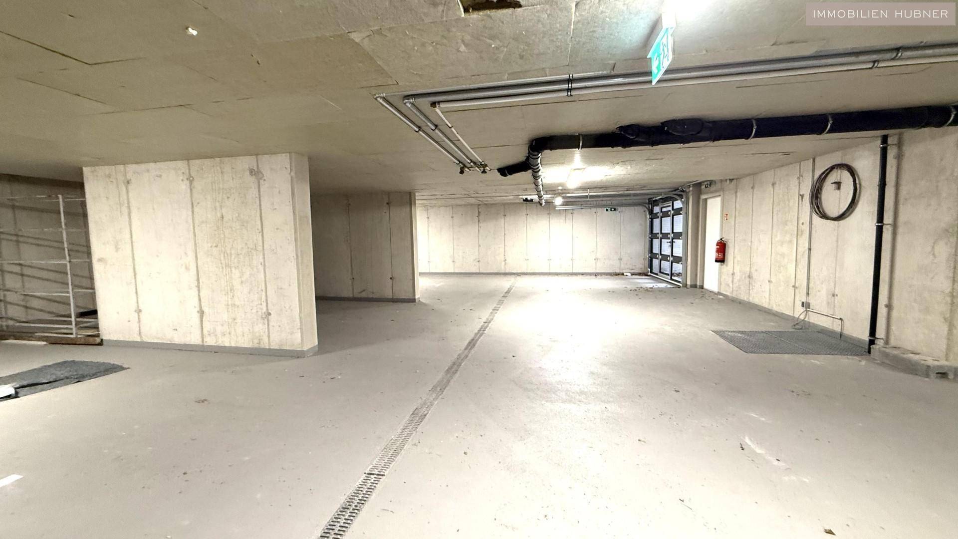 Weitläufige Tiefgarage mit Betonwänden und -decken, bereit für die Nutzung.