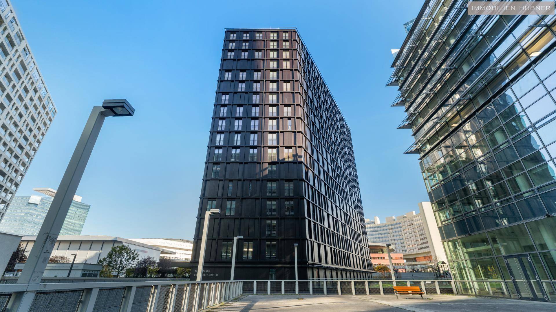 Moderne Architektur des Wohngebäudes mit dunkler Fassade und vielen Fenstern.