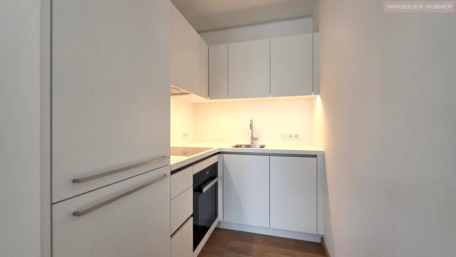 Kompakte, moderne Küche mit weißen Schränken und integrierten Geräten, ideal für kleine Wohnungen.