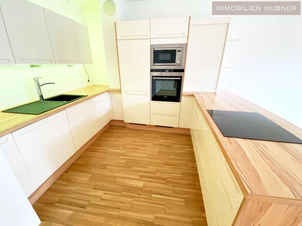 Moderne Einbauküche mit hellen Fronten, Holzarbeitsplatten und Induktionskochfeld.