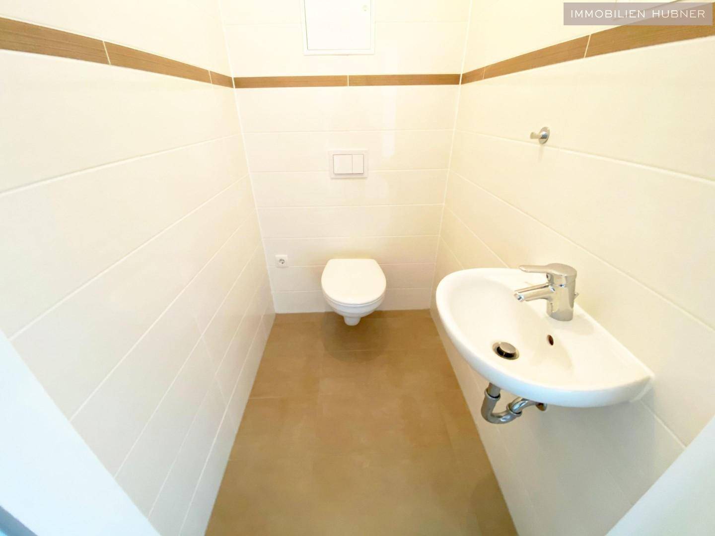 Separates Gäste-WC mit Wand-WC und kleinem Handwaschbecken.