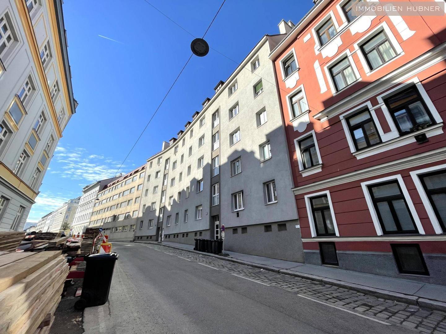 Straßenansicht mit mehrstöckigen Wohngebäuden und Baustelle im Vordergrund.