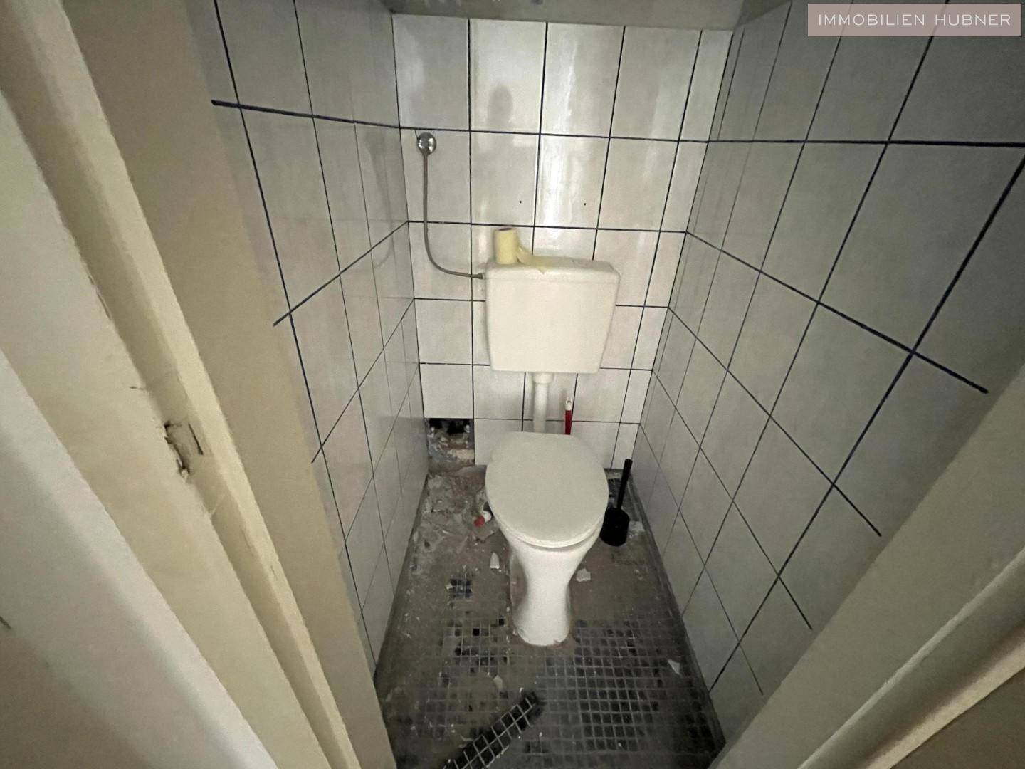Kleines WC mit weiß gefliesten Wänden und Toilette, funktional und einfach.
