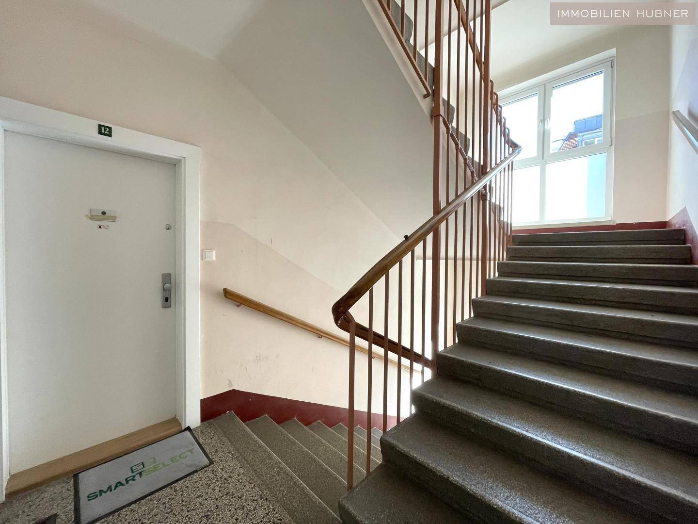 Treppenhaus mit Steinstufen und Holzgeländer, führt zu den oberen Etagen.
