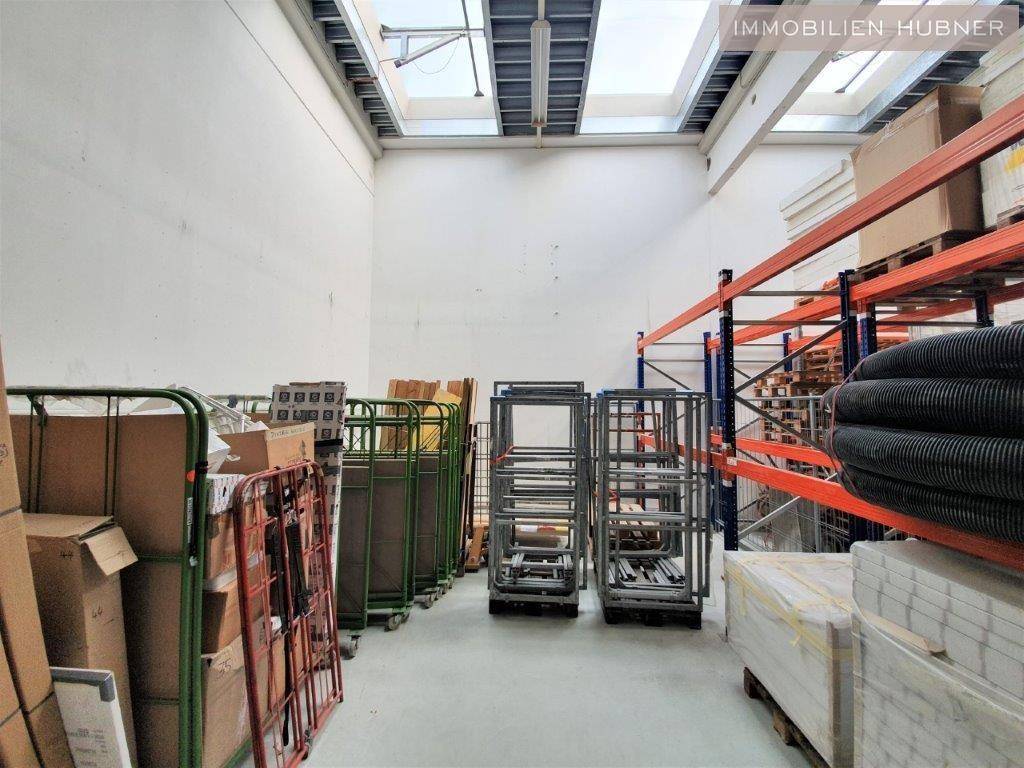 Geräumiges Lager mit hohen Decken, Oberlichtern und Metallregalen, ideal für industrielle Nutzung.