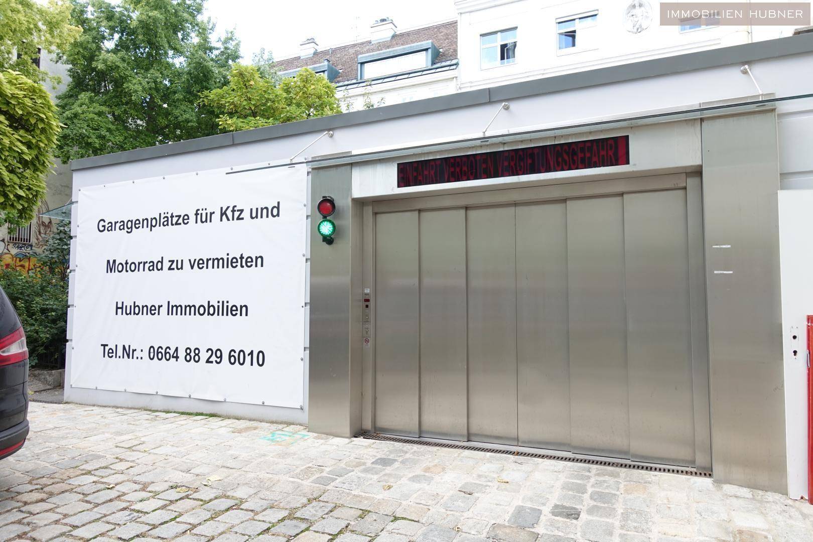 Eingang zu einer Tiefgarage mit einem Schild, das Parkplätze für Autos und Motorräder bewirbt.