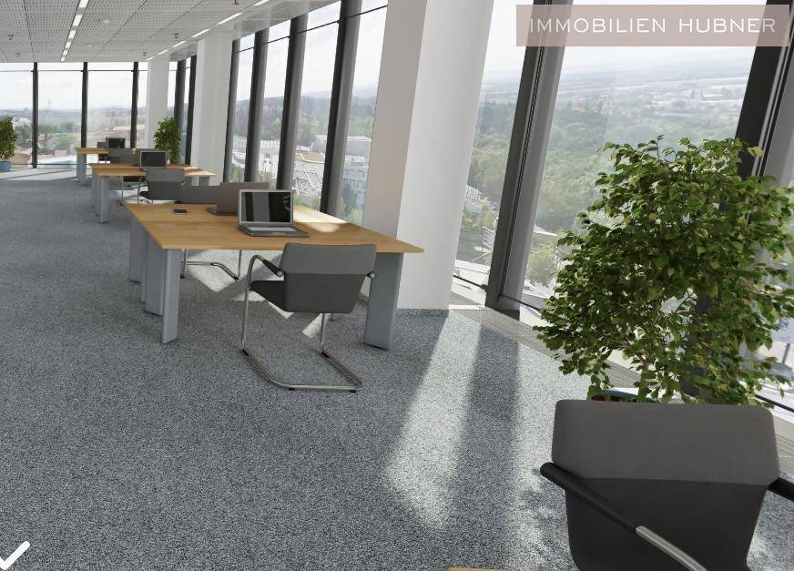 Geräumiger Bürobereich mit Schreibtischen und Stühlen, umgeben von großen Fenstern mit grüner Aussicht.