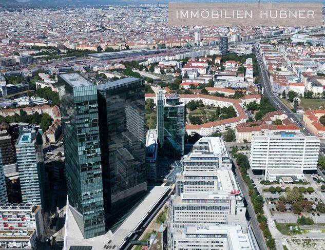 Weitläufige Luftaufnahme der Stadt mit dem markanten modernen Hochhaus und umliegenden Gebäuden.