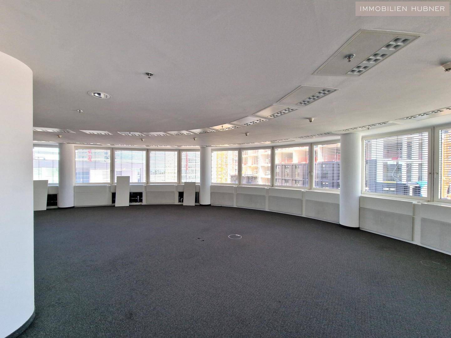 Weitläufiger Bürobereich mit vielen Fenstern und Säulen, der eine flexible Raumaufteilung ermöglicht.