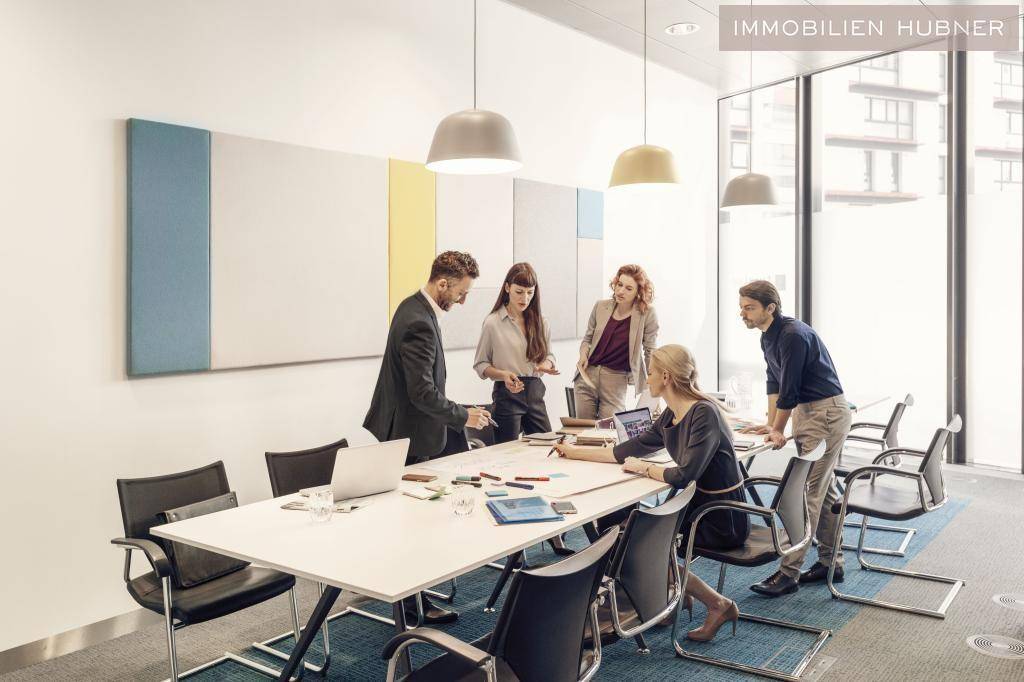 Kreativer Konferenzraum mit modernem Design, großem Tisch und farbigen Akustikpaneelen für inspirierende Besprechungen.