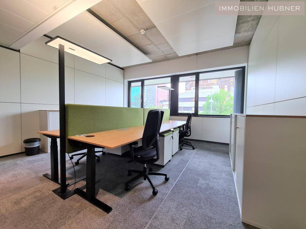 Helles Büro mit ergonomischen Schreibtischen, Teppichboden und schallabsorbierenden Deckenplatten für eine angenehme Arbeitsatmosphäre.