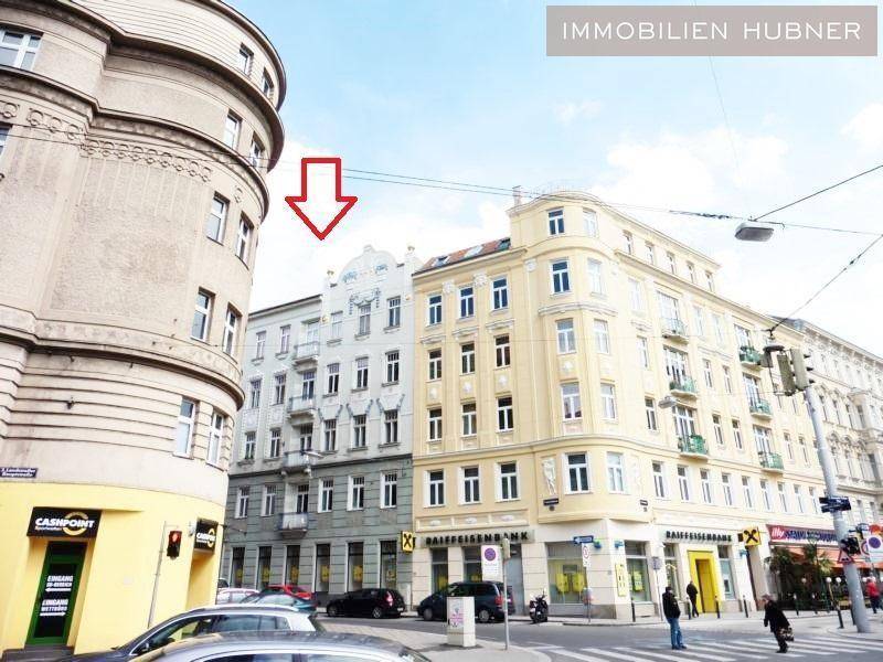 Straßenansicht einer Stadtkreuzung mit mehreren Gebäuden, darunter das Immobilienobjekt, markiert mit einem Pfeil.