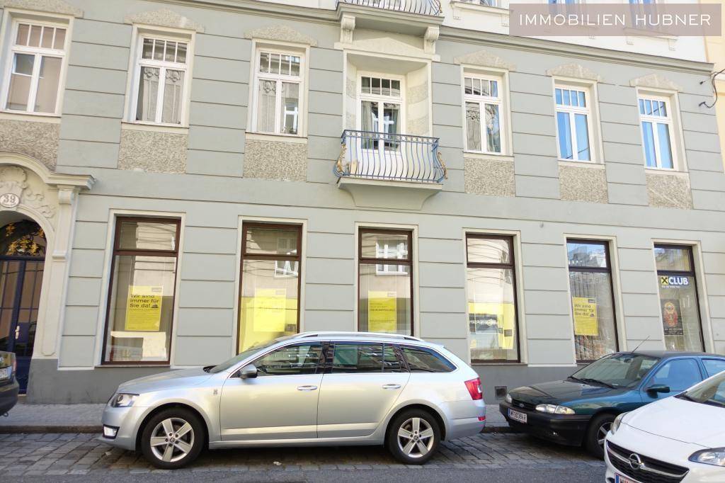 Historische Gebäudefassade mit vielen Fenstern und Mietanzeigen, Autos parken auf der Straße.