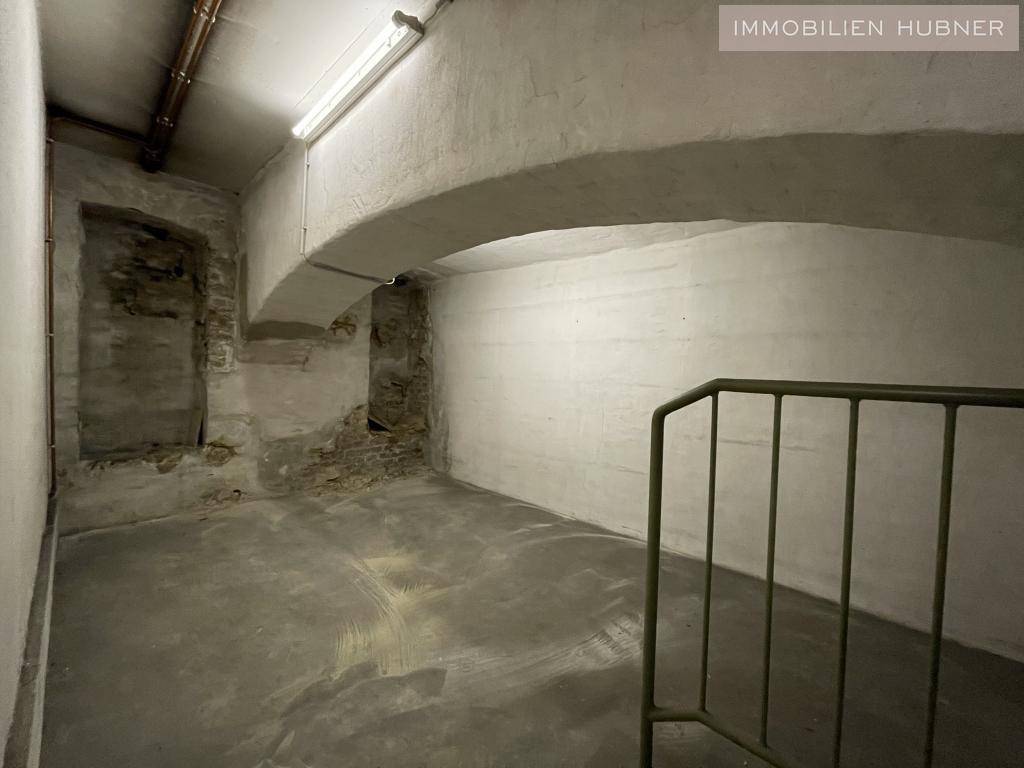 Alter Kellerraum mit Gewölbedecken, Betonboden und teilweise freigelegten Steinwänden, rustikaler Charme.