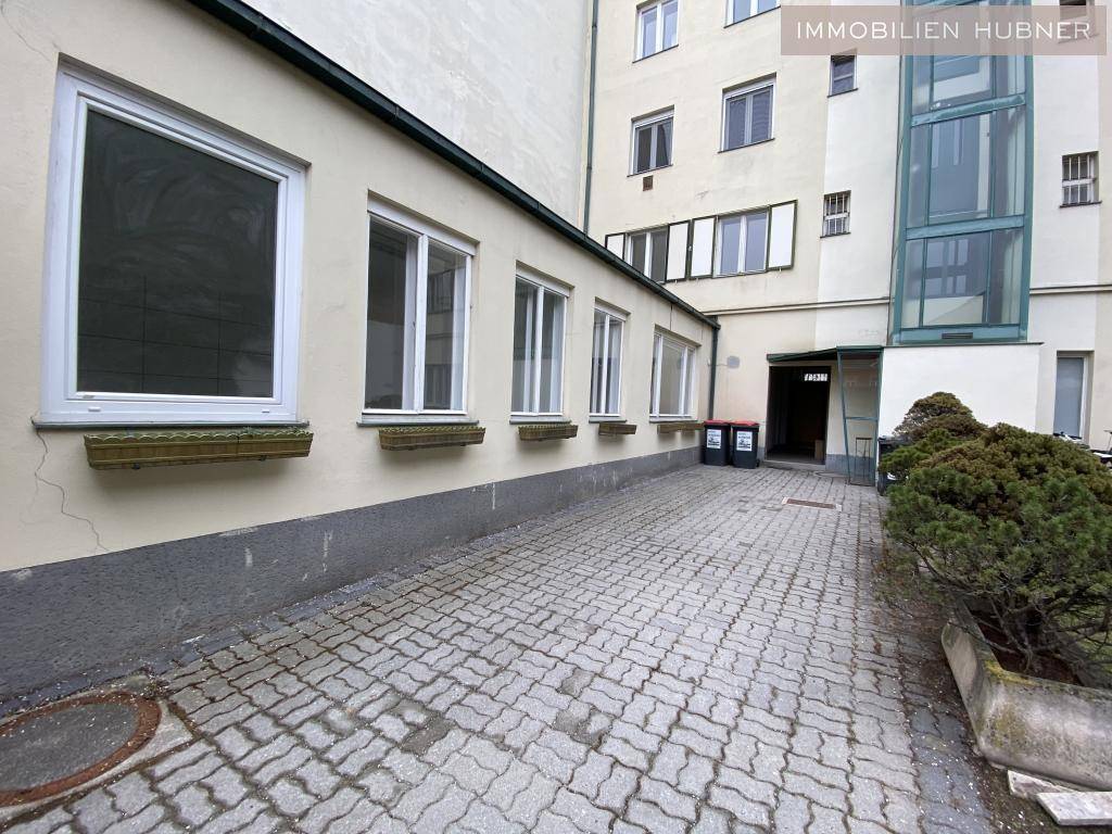 Gepflasterter Innenhof mit Fenstern des Gebäudes und einem Blick auf den Aufzug im Hintergrund.