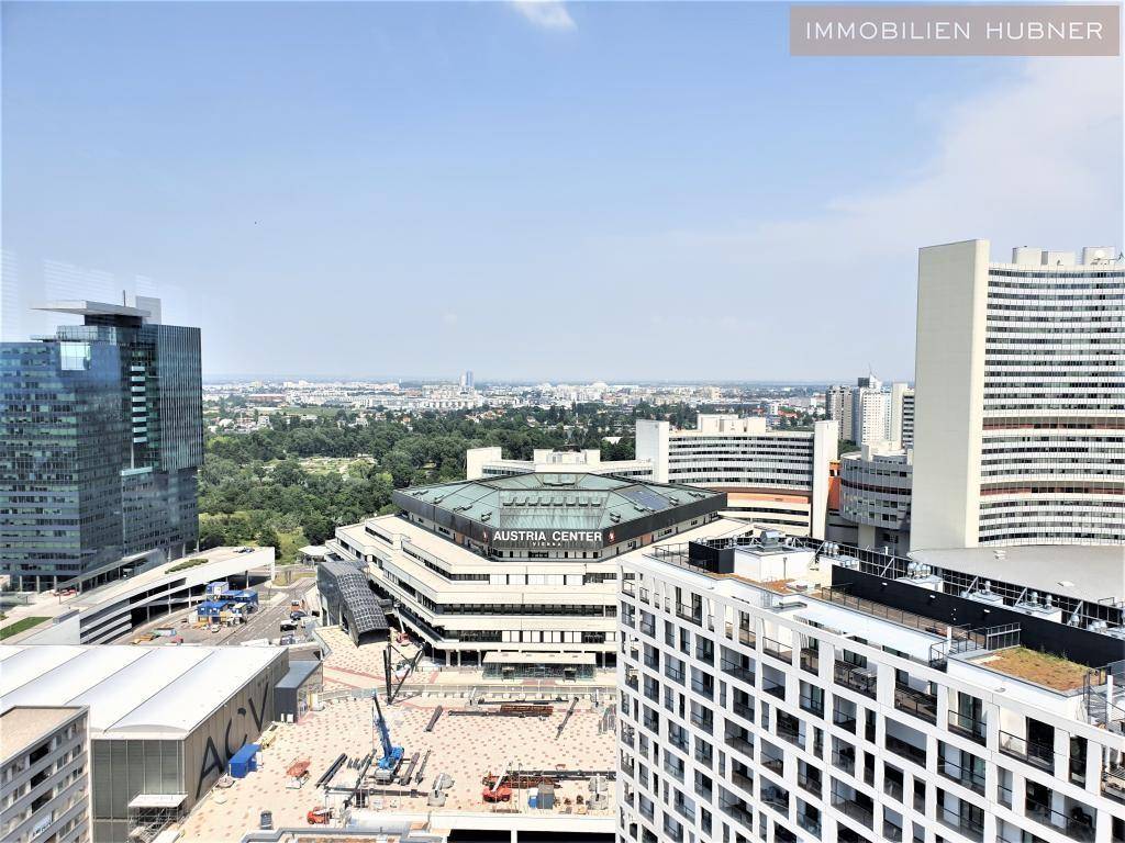 Panoramablick auf eine moderne Stadtlandschaft mit Hochhäusern, einem Kongresszentrum und Baustellenaktivitäten.