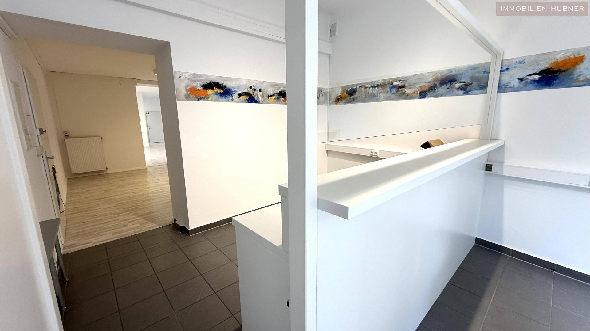 Innenansicht eines Bürobereichs mit Theke und Übergang zu weiteren Räumen.