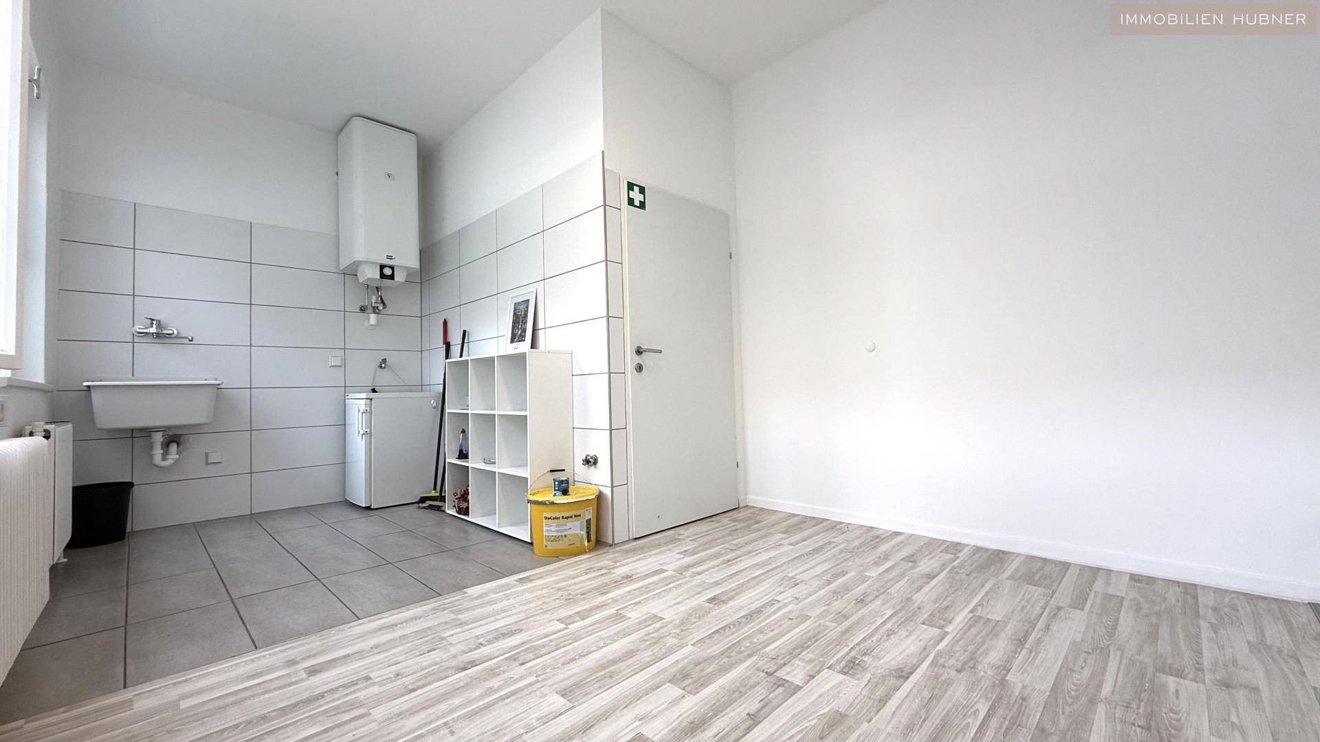 Hauswirtschaftsraum mit Waschbecken, Boiler, Fliesenboden und einem Regal.