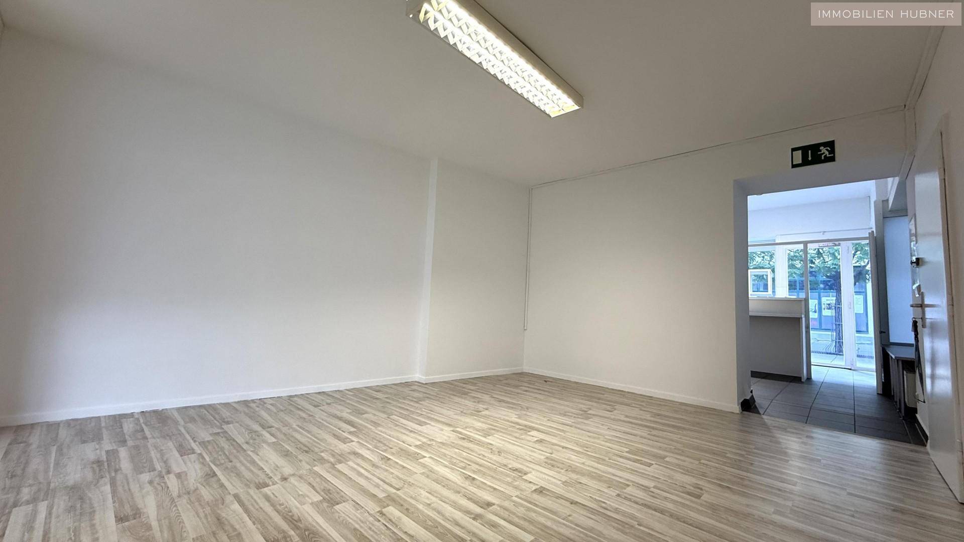 Geräumiger Büroraum mit Laminatboden und einem Blick in einen angrenzenden Bereich.