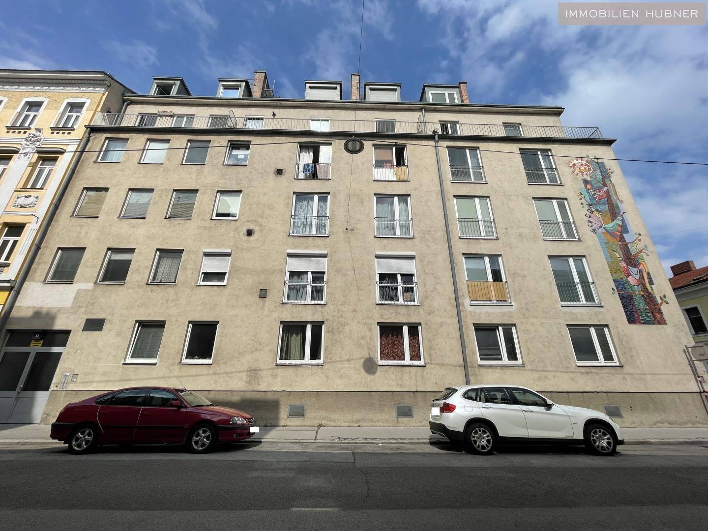 Fassade eines Mehrfamilienhauses mit vielen Fenstern und kleinen französischen Balkonen.