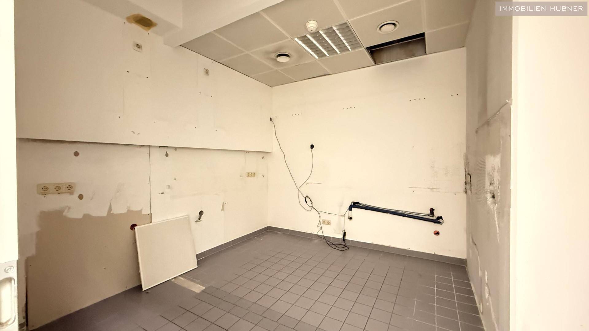 Raum in Renovierung mit Fliesenboden, freiliegenden Wänden und Deckenplatten.