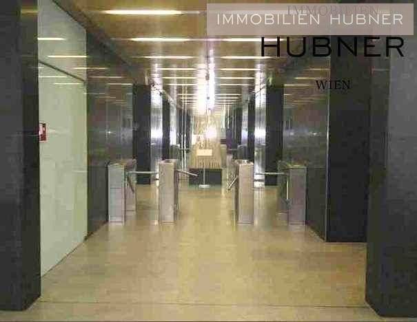 Moderner Eingangsbereich mit Sicherheitsschleusen und glänzenden Oberflächen in einem Bürogebäude.