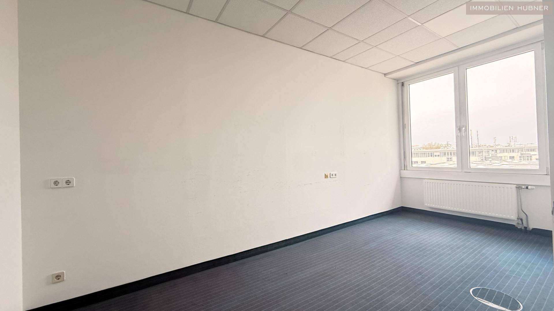Schlichtes Büro mit Teppichboden und mehreren Steckdosen an der Wand, ideal für Arbeitsplätze.