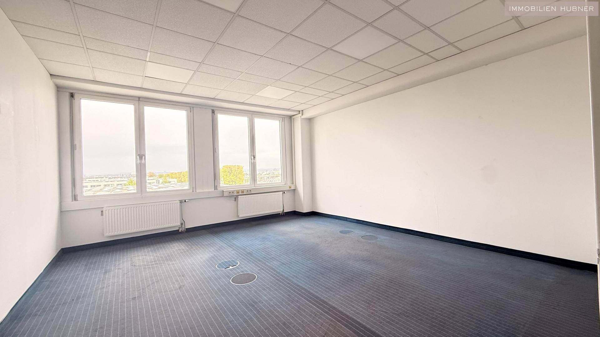 Helles Büro mit Teppichboden und weitem Ausblick durch die Fenster, ideal für Arbeitsplätze.