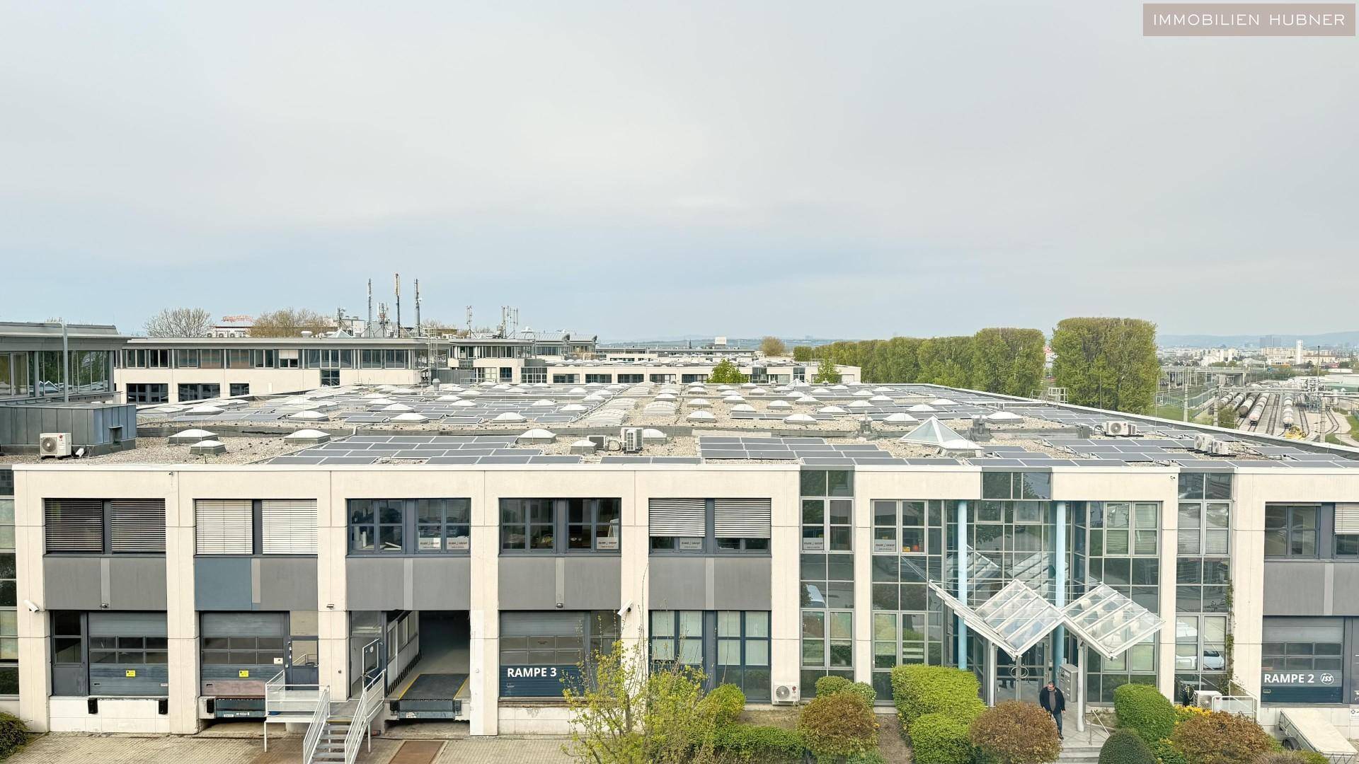 Großes Geschäftsgebäude mit moderner Architektur, Photovoltaikanlage auf dem Dach und Laderampen.
