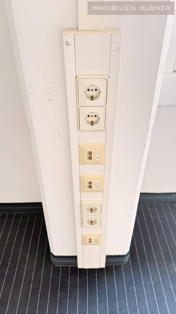 Vertikale Stromsäule mit mehreren Steckdosen und Netzwerkanschlüssen im Büro.