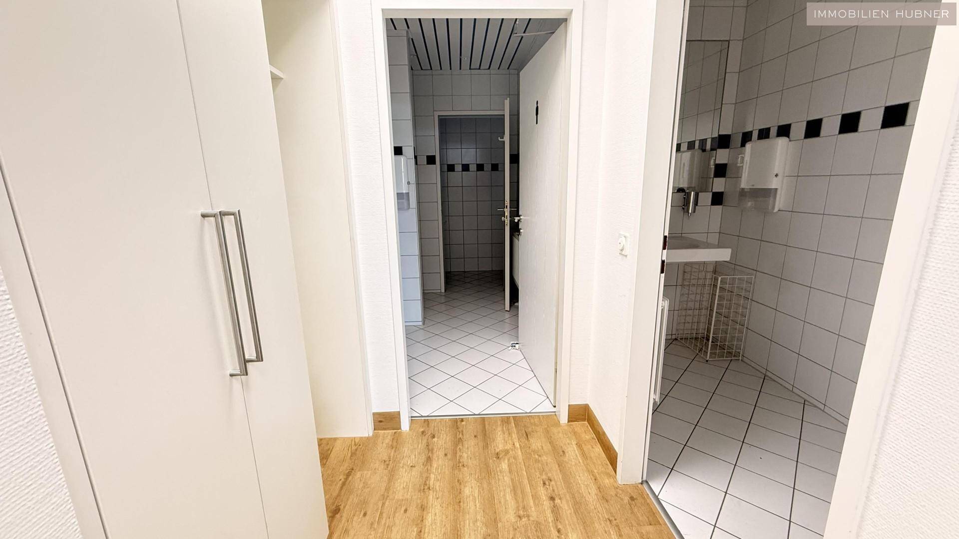 Blick auf zwei Türen, die zu gefliesten Sanitärbereichen führen, mit einem Einbauschrank im Vordergrund.